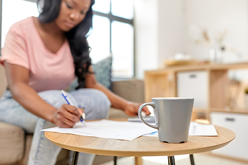 Image showing african woman with papers and calculator at home