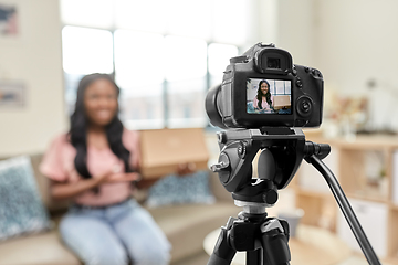 Image showing female video blogger with camera and box at home