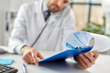 Image showing male doctor calling on desk phone at hospital