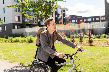 Image showing smiling young man riding bicycle on city street