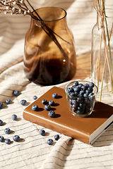 Image showing cup of blueberry, book and dried flowers in vases