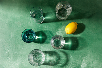 Image showing glasses with water and lemons on green background