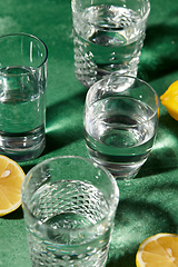 Image showing glasses with water and lemons on green background