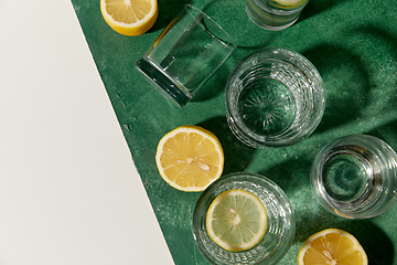 Image showing glasses with water and lemons on green background