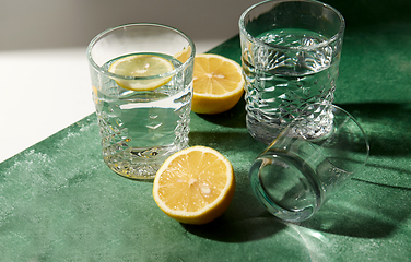 Image showing glasses with water and lemons on green background