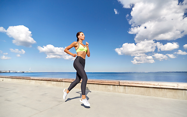 Image showing young woman running along sea promenade