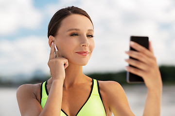 Image showing woman with earphones and smartphone doing sports