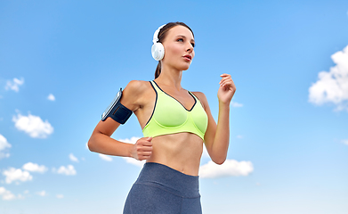 Image showing woman with headphones and smartphone running