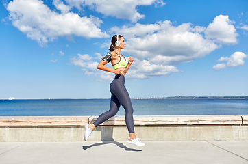 Image showing woman with headphones and smartphone running