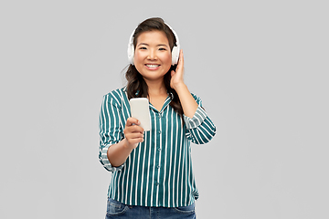 Image showing happy asian woman in headphones listening to music