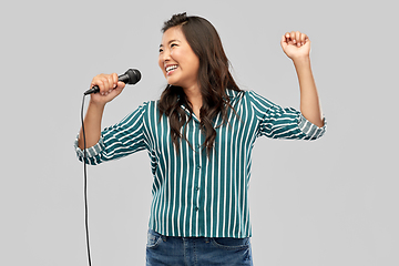 Image showing happy asian woman with microphone singing