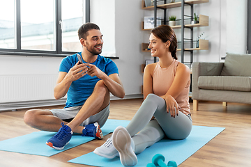 Image showing happy couple with smartphone doing sports at home