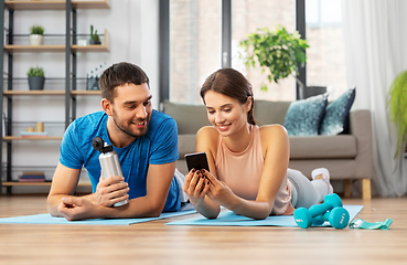 Image showing happy couple with smartphone after sports at home