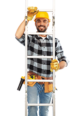 Image showing happy male builder in helmet climbing up ladder