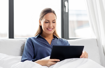 Image showing young woman with tablet pc in bed at home bedroom