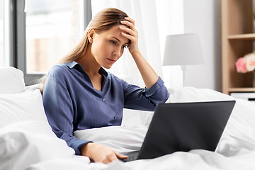 Image showing stressed young woman with laptop in bed at home