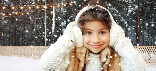 Image showing girl in earmuffs at ice skating rink in winter