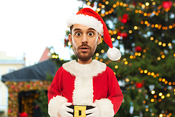 Image showing surprised man in santa costume over christmas tree