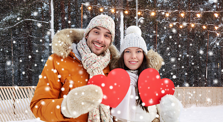 Image showing happy couple with red hearts at ice rink in winter