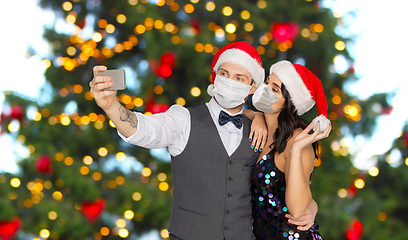Image showing couple in medical masks taking selfie on christmas