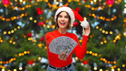 Image showing happy woman in santa hat with money on christmas