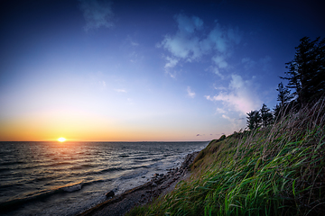 Image showing Sunset by the ocean coast under a blue sky