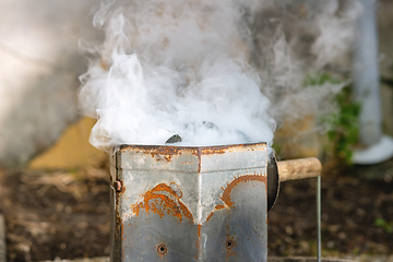 Image showing Coal heater in rusty metal with smoke