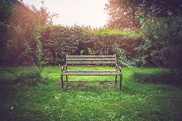 Image showing Old wooden bench in a park on a green lawn