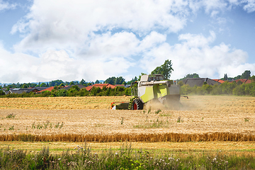 Image showing Harvester near the city on a golden field.