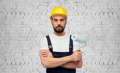 Image showing male builder with paint roller over brick wall