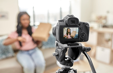 Image showing female video blogger with camera and box at home