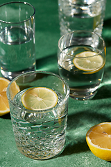 Image showing glasses with water and lemons on green background