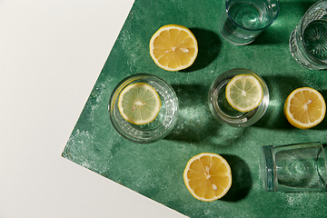 Image showing glasses with water and lemons on green background