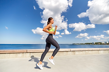 Image showing young woman running along sea promenade