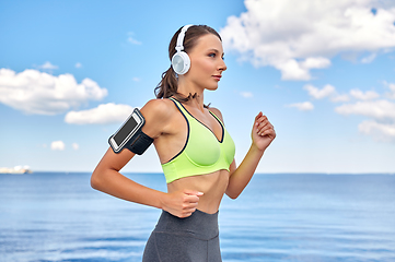 Image showing woman with headphones and smartphone running