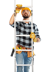 Image showing male builder in helmet climbing up ladder