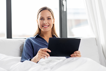 Image showing young woman with tablet pc in bed at home bedroom