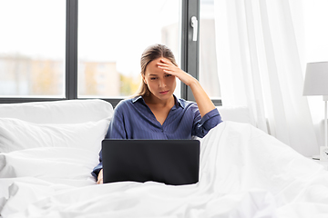 Image showing stressed young woman with laptop in bed at home