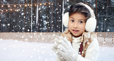 Image showing girl in earmuffs at ice skating rink in winter