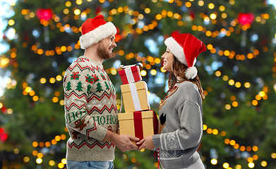 Image showing happy couple in christmas sweaters with gifts