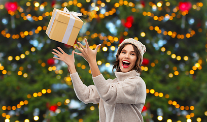 Image showing young woman in winter hat catching gift box