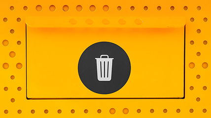 Image showing Yellow trash can close-up with a black sticker