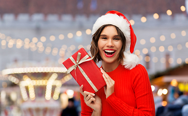 Image showing happy young woman in santa hat with red gift box