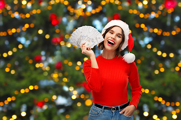 Image showing happy woman in santa hat with money on christmas