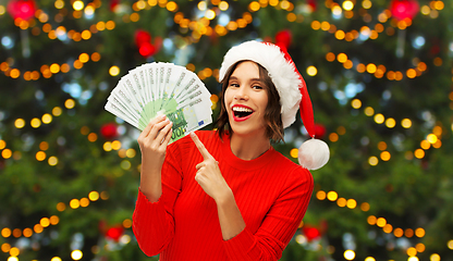 Image showing happy woman in santa hat with money on christmas