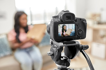 Image showing female video blogger with camera and box at home