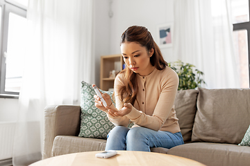 Image showing asian woman making blood test with glucometer at home