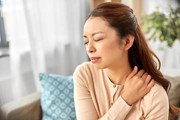 Image showing asian woman suffering from ache in neck at home