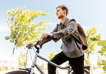 Image showing teenage boy with earphones and bag riding bicycle