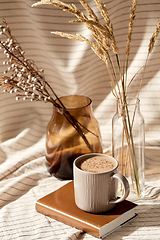 Image showing cup of coffee on book and dried flowers in vases